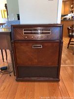 Front view of the Philco radio cabinet showing tuner dial, knobs, and lower fabric speaker covering.