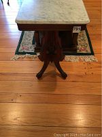Front view showing marble top and carved wooden base.