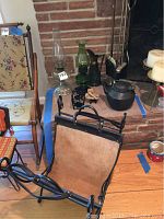 Photo showing the entire lot including two oil lamps, a black cast iron teapot, fireplace andirons, and a fireplace tool set arranged near a brick fireplace.