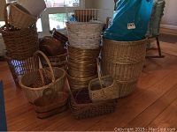 Multiple wicker baskets of various sizes, white plastic wastebasket, gold round baskets, and wooden basket in natural and white finishes stacked together in a room.