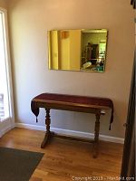 Foyer table with burgundy runner against wall under mirror