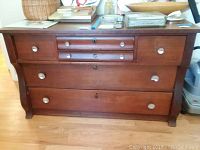 Full view of the wooden sideboard with five drawers and metal knob handles, showing its medium-brown finish and wood grain.