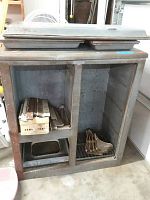 Disassembled vintage ice cabinet body showing metal interior and wooden exterior frame with items inside.