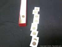 View of individual coins outside the box laid on black background showing different coin faces and sizes.
