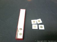 Long red box filled with numerous US 1 cent pennies in 2x2 holders arranged vertically, some coins placed outside holders on black cloth background
