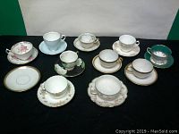 Image showing all ten assorted teacups and saucers arranged on black background to capture full lot