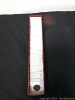 Top view of coins in a red box, each coin individually packaged in white cardboard holders with handwritten labels.