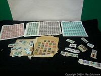 Full view of multiple sheets and loose stamps arranged on table with a green and white background