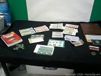 Full lots of Canadian currency, coins, foreign notes and publications spread on table