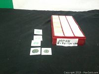 Box of Japanese coins in individual holders and a red storage box labeled for 5, 50, 100 yen coins.