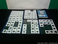 Full view of Haitian coin collection arranged in several sheets and a coin collecting guide book