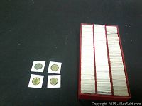 Four coins outside the box shown on left side with red storage tray on right filled with coins in holders.