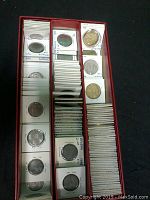 Several rows of vintage Belgium coins in white cardboard coin holders with handwritten labels, organized inside a red segmented box.
