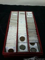 Red box holding many Dutch coins in white holders, with handwritten labels showing years and denominations