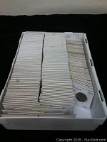 White plastic bin filled with neatly arranged coin flips holding individual coins, mostly labeled with countries or years such as Panama and Serbia.