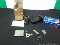 Lot with Nikon 55-200mm lens and box, zoom slide duplicator and box, two silver plated lighters, cigarette case, chromatic pitch, and small folding knife on black surface