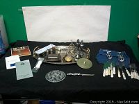 Full lot arrangement on black cloth including silver plated tray, cutlery, wine openers, candlestick holder, salt and pepper shakers, glass dish, pamphlets