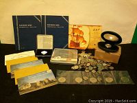 Wide view showing collector books, loose coins, commemorative booklet, and boxed silver coin.