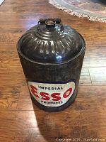 Front view of cylindrical vintage metal oil container with 'Imperial Esso Products' label in red and blue on front.