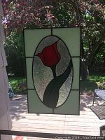 Full view of the stained glass panel showing the red tulip design in an oval center with surrounding textured and frosted glass panels.
