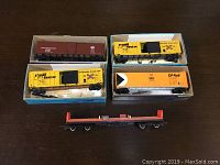 Top view showing all five freight cars, three yellow Rail Box boxcars, one brown Pennsylvania, one orange CP Rail, and one red flatbed, some in original boxes. Extra hitches visible.
