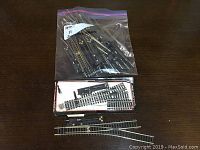 11 pieces of HO scale model train switching track displayed on a wood surface with some pieces in a box and some in a plastic bag.
