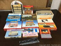 Overview of various boxed model kits and accessories for model train layouts, colorful packaging showing Victorian shops, houses, tram, and other accessories.