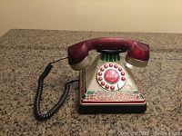 Front view of the Coca-Cola stained glass look rotary phone showing dial, handset, and decorative base.