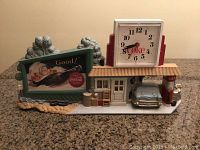 Front view of the full Coca-Cola wall display showing the vintage gas station setup with the clock on top.