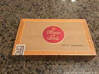 Top view of sealed wooden cigar box with House of Lords red logo and 'Petit Coronas' text.