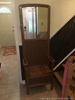 Full view of wooden entrance furniture piece with mirror and seat with arms