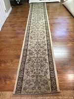 Full length view of the carpet runner on hardwood floor showing the pattern and condition.