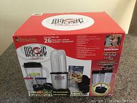 Box front showing Magic Bullet Deluxe logo and image of blender pieces with 26-piece count and product features
