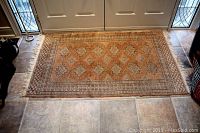 Top view of wool area rug with intricate geometric patterns and fringed edges.