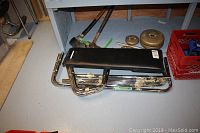 Workout bench seat and metal frame parts disassembled on floor with some weights nearby