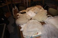 Photo showing multiple vintage lace, crochet and tulle textile pieces laid out on table, showcasing different textures and styles.