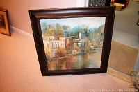 Framed painting showing full artwork and frame with wall and carpet background.