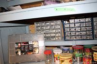 Wide view of shelf with multiple parts cabinets, jars, and tins filled with various hardware items
