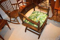 Full view of vintage ornate dark wood chair with cane seat and floral cushion, surrounded by other wooden chairs.