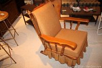 Front angle view of wood framed rocking chair with brown fabric cushions and skirted base.