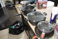 Full overview of the collection of pots and pans plus accessories including strainer and box in background