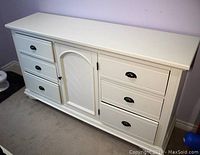 Front view of white wooden dresser with six drawers and central cabinet door with chevron pattern.