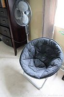 Noma metal fan and foldable papasan chair in carpeted room near window