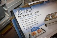 Damaged box of Oster Triple Buffet Server with French and English text describing features.