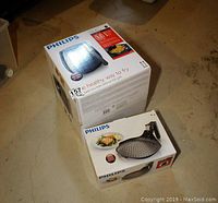 Overhead view of two original Philips boxes: larger Airfryer Plus box and smaller Airfryer Grill Pan box on concrete floor