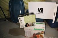 Photo showing boxed juicer, Umbra wall decor box, and Roasting pan boxes overlapping with blue roasting pan covers visible