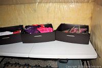Three black woven baskets on a white folding table containing various colorful lingerie items, some packaged.