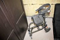 Front-angle photo of the walker showing padded handles, storage pouch, wheels and legs.