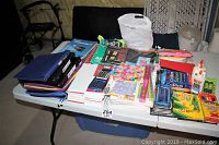 Wide view of assorted new school supplies on table including binders, papers, crayons, calculators