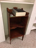 Front view of vintage wooden stand with large encyclopedia on top showing size and condition of stand.